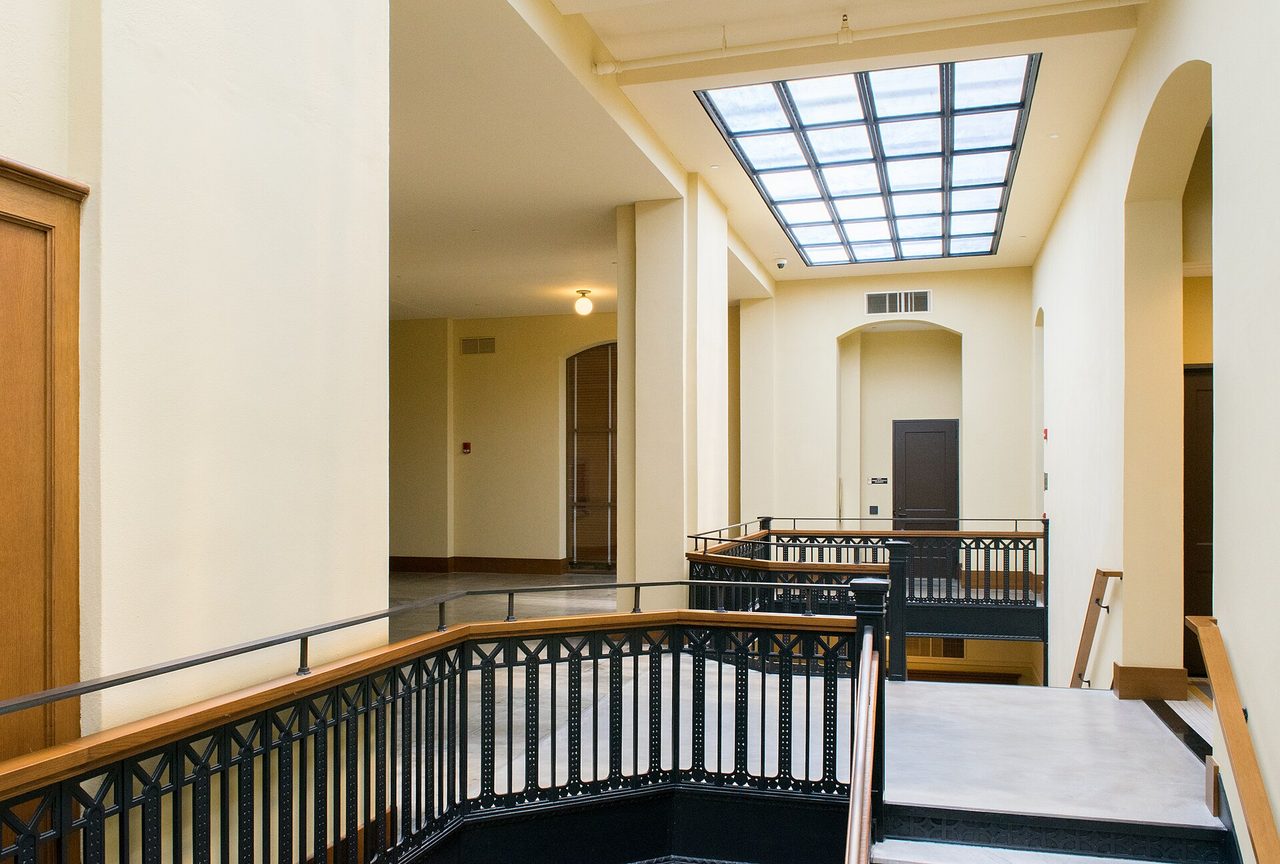 Inside the restored 1910 Harris County Courthouse in Houston: a skylit upper hall with cast-iron railings.