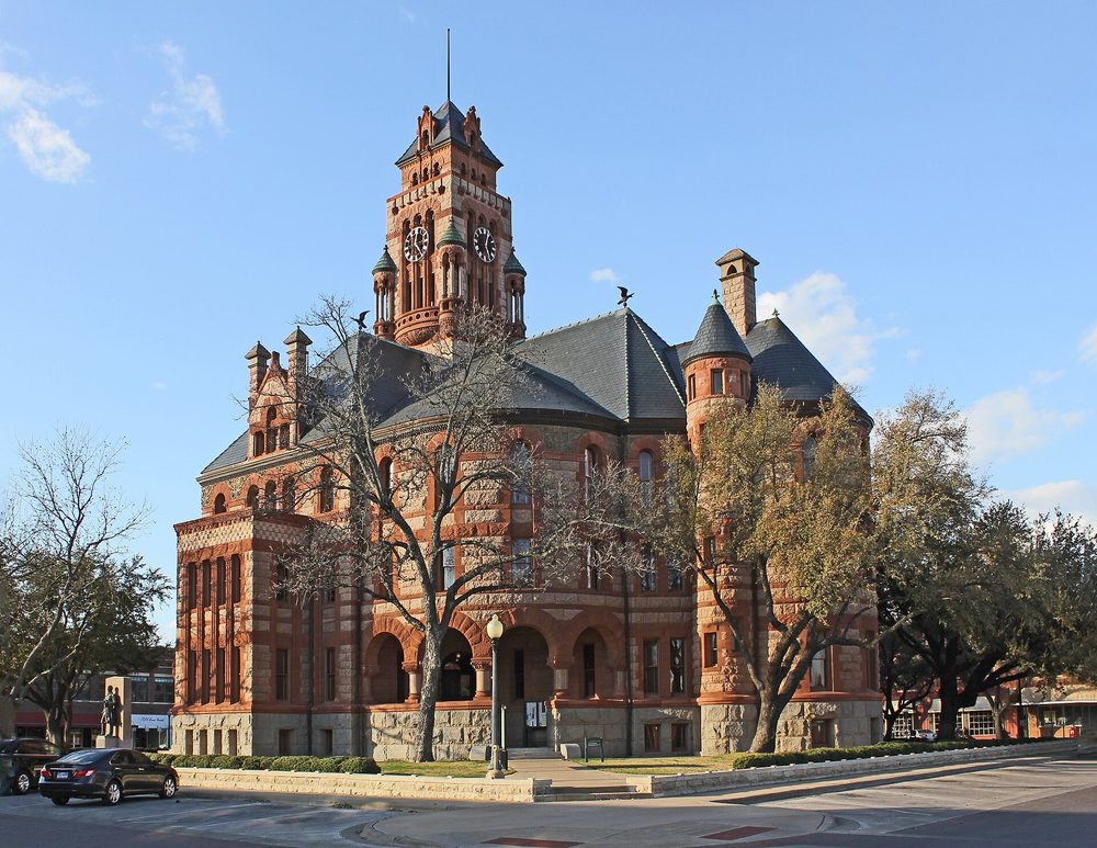 The Ellis County Courthouse in Waxahachie, red sandstone and granite with a tall clock tower.